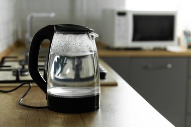 Modern electric transparent kettle on a wooden table in the kitchen.Kettle for boiling water and making tea.Home appliances for making hot drinks.Space for copy.Place for text.