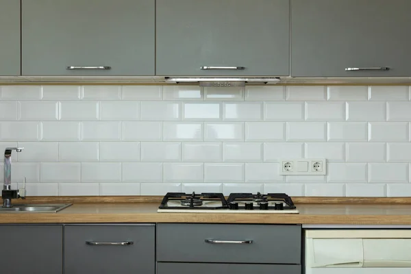 Interior of a modern comfortable kitchen. Renting a modern home or selling a new apartment. Bright kitchen with utensils, cabinets and a gas stove. Minimalist style. Empty space. Real estate concept.