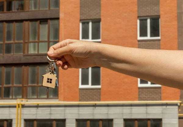 A woman holds the keys to a new quart or house. The keys open and close the door lock. The owner opens the door of a new house. The concept of selling and renting real estate.