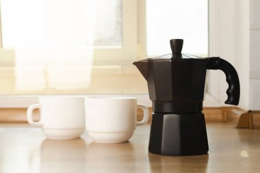 Metal coffee maker in the kitchen. Geyser coffee maker with coffee cups on the background of a brown table.Concept morning.Morning coffee. Place to copy. Place for text.