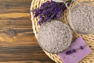 Lavender spa. Sea salt, lavender flowers, essential oils, body cream and handmade soap. Natural herbal cosmetics with lavender flowers on brown texture background. Relax and spa concept. Space for text.