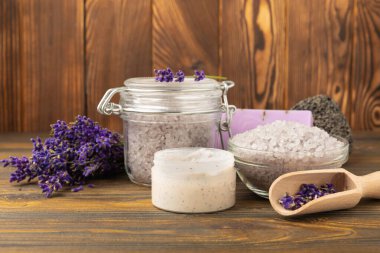 Lavender spa. Sea salt, lavender flowers, essential oils, body cream and handmade soap. Natural herbal cosmetics with lavender flowers on brown texture background. Relax and spa concept. Space for text.
