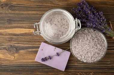 Lavender spa. Sea salt, lavender flowers, essential oils, body cream and handmade soap. Natural herbal cosmetics with lavender flowers on brown texture background. Relax and spa concept. Space for text.