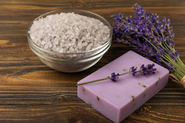 Lavender spa. Sea salt, lavender flowers, essential oils, body cream and handmade soap. Natural herbal cosmetics with lavender flowers on brown texture background. Relax and spa concept. Space for text.
