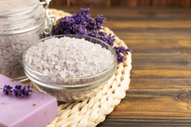 Lavender spa. Sea salt, lavender flowers, essential oils, body cream and handmade soap. Natural herbal cosmetics with lavender flowers on brown texture background. Relax and spa concept. Space for text.