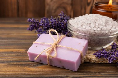Lavender spa. Sea salt, lavender flowers, essential oils, body cream and handmade soap. Natural herbal cosmetics with lavender flowers on brown texture background. Relax and spa concept. Space for text.