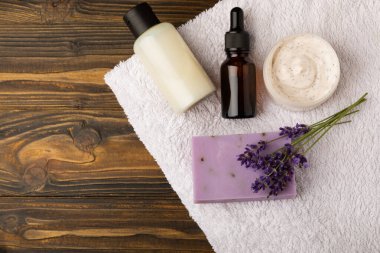 Lavender spa. Sea salt, lavender flowers, essential oils, body cream and handmade soap. Natural herbal cosmetics with lavender flowers on brown texture background. Relax and spa concept. Space for text.