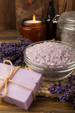 Lavender spa. Sea salt, lavender flowers, essential oils, body cream and handmade soap. Natural herbal cosmetics with lavender flowers on brown texture background. Relax and spa concept. Space for text.