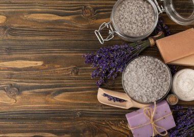 Lavender spa. Sea salt, lavender flowers, essential oils, body cream and handmade soap. Natural herbal cosmetics with lavender flowers on brown texture background. Relax and spa concept. Space for text.