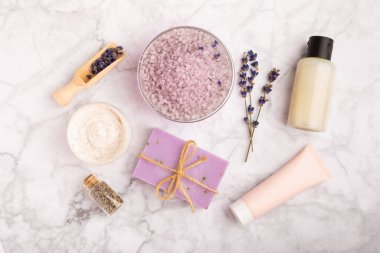 Lavanta spreyi, deniz tuzu, lavanta çiçekleri, aroma mumu, vücut kremi ve el yapımı sabun. Mermer arka planda lavanta çiçekleri olan doğal bitkisel kozmetik ürünleri. Rahatlayın. Güzellik tedavileri..