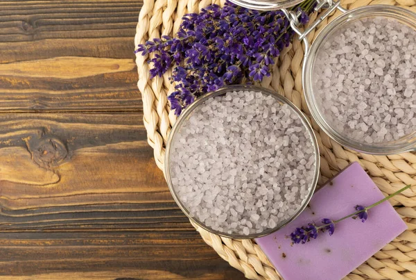 Lavender spa. Sea salt, lavender flowers, essential oils, body cream and handmade soap. Natural herbal cosmetics with lavender flowers on brown texture background. Relax and spa concept. Space for text.