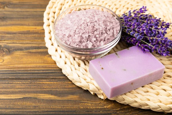 Lavender spa. Sea salt, lavender flowers, essential oils, body cream and handmade soap. Natural herbal cosmetics with lavender flowers on brown texture background. Relax and spa concept. Space for text.