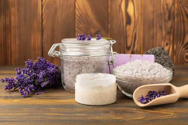 Lavender spa. Sea salt, lavender flowers, essential oils, body cream and handmade soap. Natural herbal cosmetics with lavender flowers on brown texture background. Relax and spa concept. Space for text.