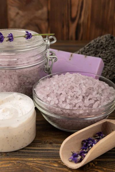 Lavender spa. Sea salt, lavender flowers, essential oils, body cream and handmade soap. Natural herbal cosmetics with lavender flowers on brown texture background. Relax and spa concept. Space for text.