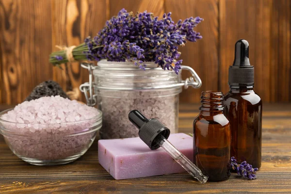 Lavender spa. Sea salt, lavender flowers, essential oils, body cream and handmade soap. Natural herbal cosmetics with lavender flowers on brown texture background. Relax and spa concept. Space for text.