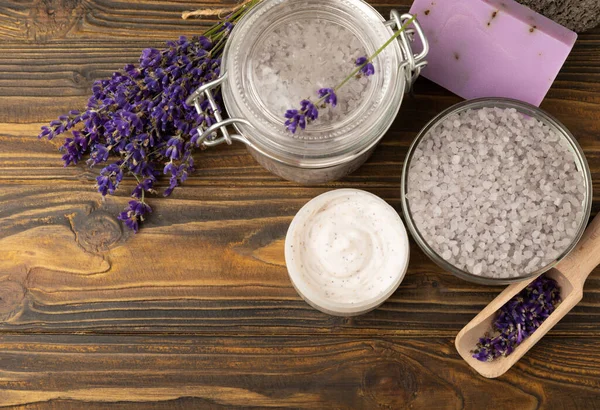 Lavender spa. Sea salt, lavender flowers, essential oils, body cream and handmade soap. Natural herbal cosmetics with lavender flowers on brown texture background. Relax and spa concept. Space for text.