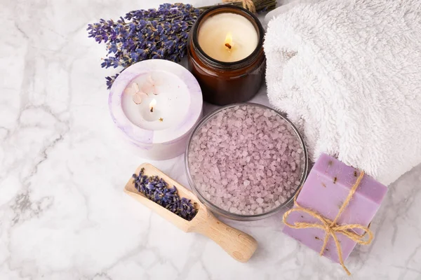 Lavender spa.Sea salt,lavender flowers,aroma candle,body cream and handmade soap.Natural herbal cosmetics with lavender flowers on marble background.Relax concept.Beauty treatments.Copy space.