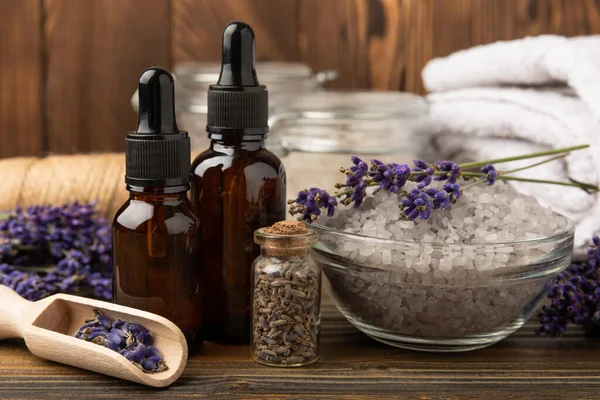 Lavender spa. Sea salt, lavender flowers, essential oils, body cream and handmade soap. Natural herbal cosmetics with lavender flowers on brown texture background. Relax and spa concept. Space for text.