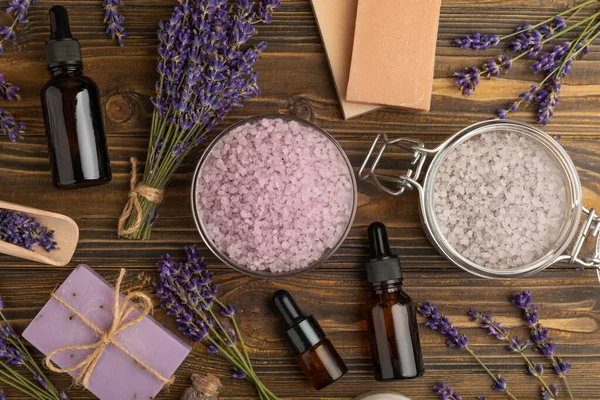 Lavender spa. Sea salt, lavender flowers, essential oils, body cream and handmade soap. Natural herbal cosmetics with lavender flowers on brown texture background. Relax and spa concept. Space for text.