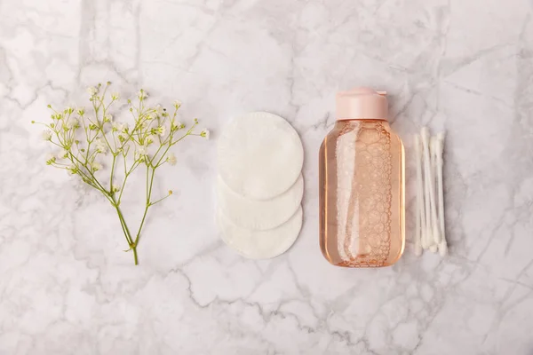 Micellar cleansing water and makeup remover pads. Skin cleansing from sebium and make-up. Composition on a white marble background. Beauty concept. Copy space text. Flat lay