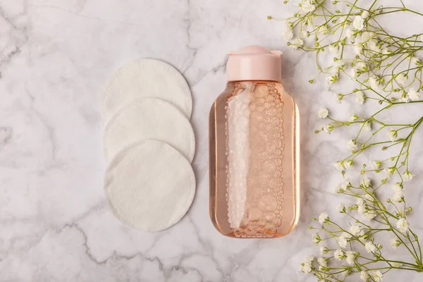 Micellar cleansing water and makeup remover pads. Skin cleansing from sebium and make-up. Composition on a white marble background. Beauty concept. Copy space text. Flat lay