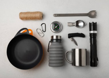 Set of tourist equipment on a white background. EDC set flat lay. Camping plate, mug, bottle, knife, rope, spoon and compass.
