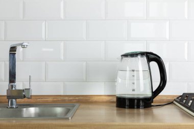 Modern electric transparent kettle on a wooden table in the kitchen.Kettle for boiling water and making tea.Home appliances for making hot drinks.Space for copy.Place for text.
