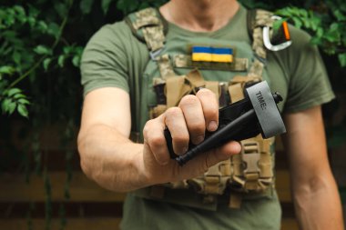 Bir asker, ilk yardımda kanı durdurmak ve kanamayı önlemek için elinde tıbbi bir turnike tutuyor. Savaş taktik ekipmanları. Savaş kullanımı Turnstil.