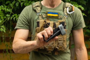 Bir asker, ilk yardımda kanı durdurmak ve kanamayı önlemek için elinde tıbbi bir turnike tutuyor. Savaş taktik ekipmanları. Savaş kullanımı Turnstil.