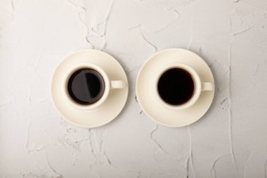 Hot coffee in a white coffee cup on a white texture table in a light atmosphere.Hot warming drink concept.Copy space.Top view.Place for text.