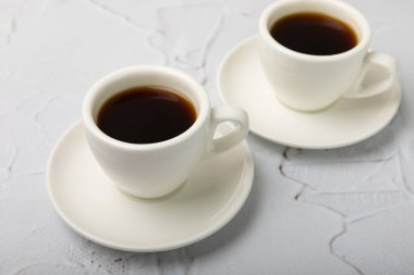 Hot coffee in a white coffee cup on a white texture table in a light atmosphere.Hot warming drink concept.Copy space.Top view.Place for text.