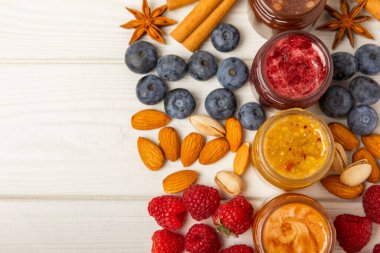 Bir kavanoz bal. Ahududulu, yaban mersinli, bademli ve şam fıstıklı meyve balı. Sağlık ve güzellik için kullanışlı güçlendirilmiş arıcılık ürünü. Bal kreması. Vejetaryen diyet organik ürün. Uzayı kopyala metin için yer