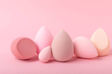 Pembe arka planda bir güzellik blenderi. Makyaj malzemesi olarak parlak süngerler. Makyaj ürünleri. Güzellik konsepti. Mesaj için yer. Kopya için yer var. Düz yatıyordu