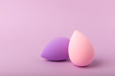 Leylak arkaplanda güzellik blenderi. Makyaj malzemesi için sünger. Makyaj ürünleri. Güzellik konsepti. Mesaj için yer. Kopya için yer var. Düz yatıyordu