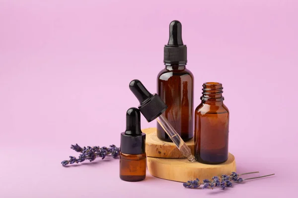 Essential oil of lavender in a glass bottle with a pipette on a pink background.Bottle with fragrant oil. essential oil mockup with copy space.Flat lay.serum.Close up.