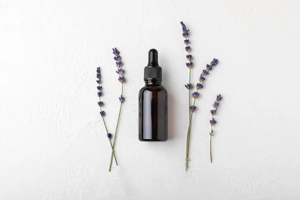 Essential oil of lavender in a glass bottle with a pipette on a white texture background.Bottle with fragrant oil. essential oil mockup with copy space.Flat lay.serum.Close up.