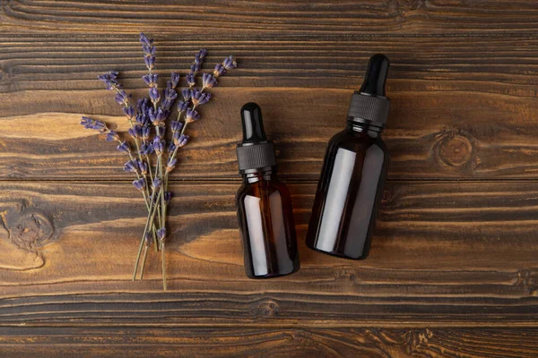 Essential oil of lavender in a glass bottle with a pipette on a brown textural background.Bottle with fragrant oil. essential oil mockup with copy space.Flat lay.serum.Close up.