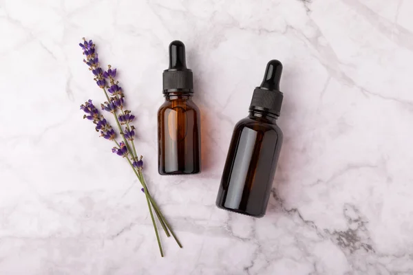 Essential oil of lavender in a glass bottle with a pipette on a white texture background.Bottle with fragrant oil. essential oil mockup with copy space.Flat lay.serum.Close up.