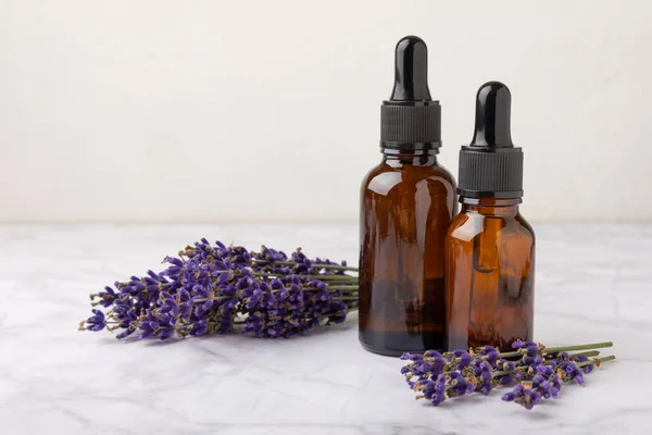 Essential oil of lavender in a glass bottle with a pipette on a white texture background.Bottle with fragrant oil. essential oil mockup with copy space.Flat lay.serum.Close up.