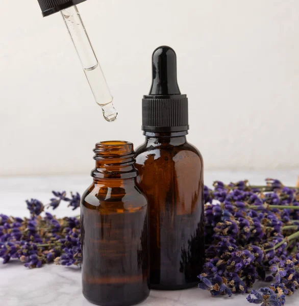 Essential oil of lavender in a glass bottle with a pipette on a white texture background.Bottle with fragrant oil. essential oil mockup with copy space.Flat lay.serum.Close up.