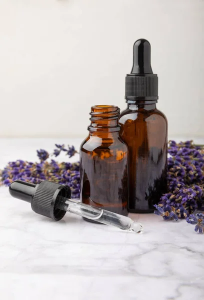 Essential oil of lavender in a glass bottle with a pipette on a white texture background.Bottle with fragrant oil. essential oil mockup with copy space.Flat lay.serum.Close up.