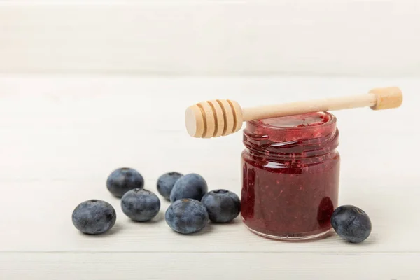 A jar of honey with blueberries on a white wood. Cold medicine. Useful fortified jam for health and beauty. Cream honey. Vegetarian diet organic product. Copy space. place for text