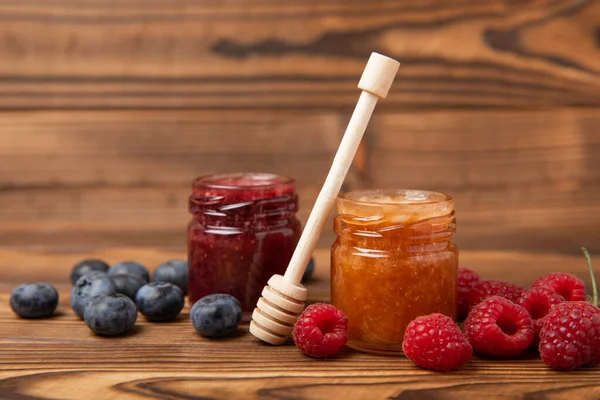 Jar of honey with blueberries and raspberries on brown wood. Cold medicine. Useful fortified jam for health and beauty. Cream honey. Vegetarian diet organic product. Copy space. place for text