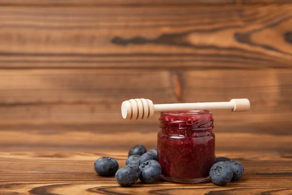 A jar of honey with blueberries on a brown wood. Cold medicine. Useful fortified jam for health and beauty. Cream honey. Vegetarian diet organic product. Copy space. place for text