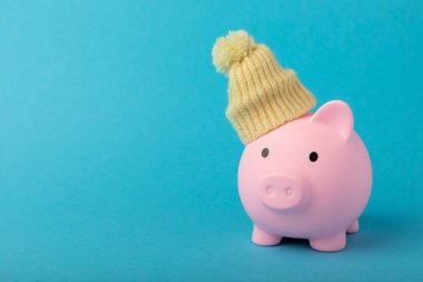 Tasarruf kavramı. Mavi desenli bir kumbara. Seni sıcak tutan, kışlık şapkalı bir kumbara. Isı tasarrufu kavramı. Mesaj için yer. Boşluğu kopyala