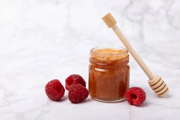 A jar of raspberry honey on a textured background. Cold medicine. Useful fortified jam for health and beauty. Vegetarian diet organic product. Copy space.place for text