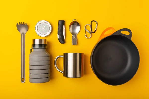 Set of tourist equipment on a yellow background. EDC set flat lay. Camping plate, mug, bottle, spoon and compass. Flat lay. Top view. Space for copy.Tourist concept. Leisure.