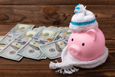 Tasarruf kavramı. Kumbaralı ve kahverengi dokuya yatırılmış para. Seni sıcak tutan, kışlık şapkalı bir kumbara. Isı tasarrufu kavramı. Mesaj için yer. Boşluğu kopyala