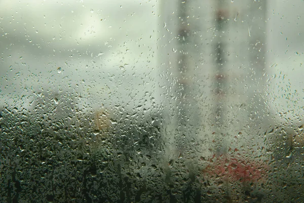 Glass with raindrops on the background of a thunderstorm. Raindrops on the background of the city.MOCKUP.Photo for design