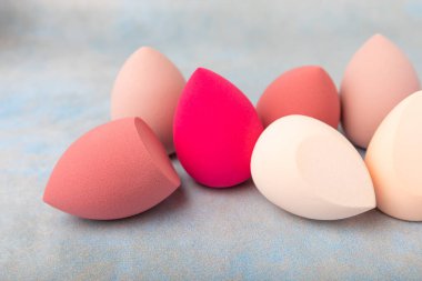 Güzellik karışımı. Mavi arka planda renkli güzellik süngerleri. Vakıf ve kapatıcı gibi ürünleri uygulamak ve harmanlamak için kozmetik araç. Uzayı kopyala metin için yer.